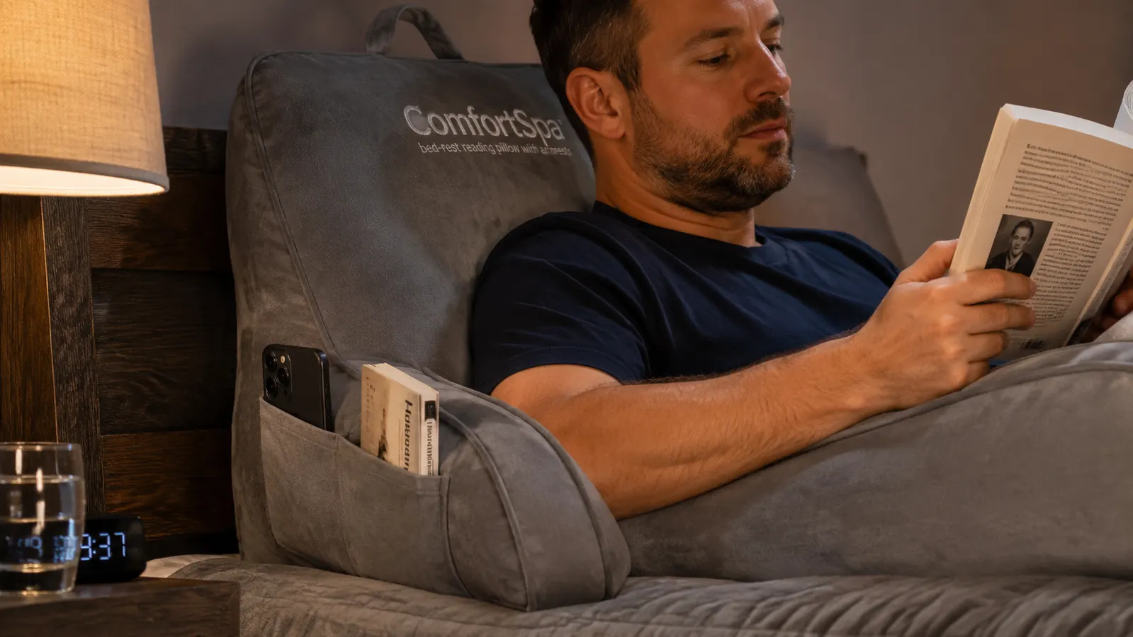Close-up of a hand resting on the armrest of a reading pillow with the side pocket visible